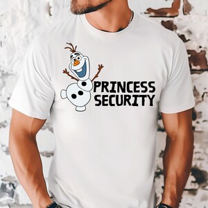 May include: White t-shirt featuring a cartoon image of Olaf the snowman with the text "PRINCESS SECURITY" in black. Olaf has a smiling face, twig arms, and a carrot nose. The shirt is a crew neck.