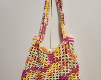 Può includere: Una borsa a mano all'uncinetto con un design a righe colorate in rosa, giallo, verde e bianco.