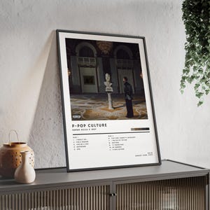 May include: A framed poster featuring the album art for "P-Pop Culture" by Karan Aujla x Ikky. The artwork shows a person in a room with a statue. The poster has a black frame and includes a tracklist.