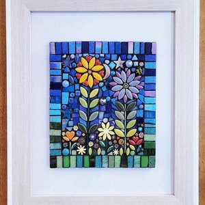 K&ouml;nnte beinhalten: Ein gerahmtes Mosaik-Kunstwerk, das eine Gartenszene mit bunten Blumen, Bl&auml;ttern und einem Halbmond vor blauem Hintergrund darstellt.