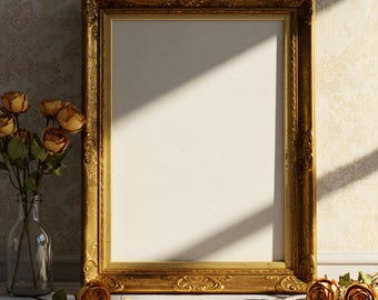 Op de afbeelding: Een gouden, sierlijke fotolijst met een leeg wit interieur staat op een wit houten oppervlak. Een heldere glazen vaas met gedroogde rozen staat links. Gedroogde rozenblaadjes en rozen zijn verspreid.
