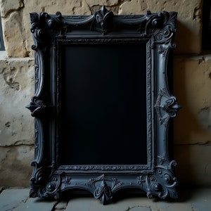 Könnte beinhalten: Ein großer, verzierter schwarzer Bilderrahmen mit aufwendigen Details. Der Rahmen hat eine rechteckige Öffnung und besteht aus einem dunklen, möglicherweise lackierten Material. Das Design umfasst florale und Rankenmotive, was ihm eine Vintage- oder Antik-Ästhetik verleiht.