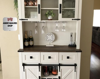 A rustic buffet with three drawers, a hutch with a rack for wine and glasses, a sliding barn door, a sideboard cupboard for the kitchen