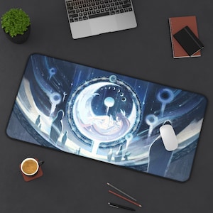 May include: A rectangular mouse mat with a celestial design, featuring a crescent moon and a figure in shades of blue, white, and purple. The mat has a black border. A laptop, mouse, and other desk items are visible on a dark surface.