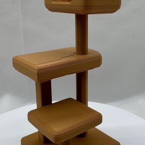 Könnte beinhalten: Ein dreistufiger Holzständer mit einem Telefonhalter oben. Der Ständer ist aus braunem Holz und hat ein schlichtes Design.