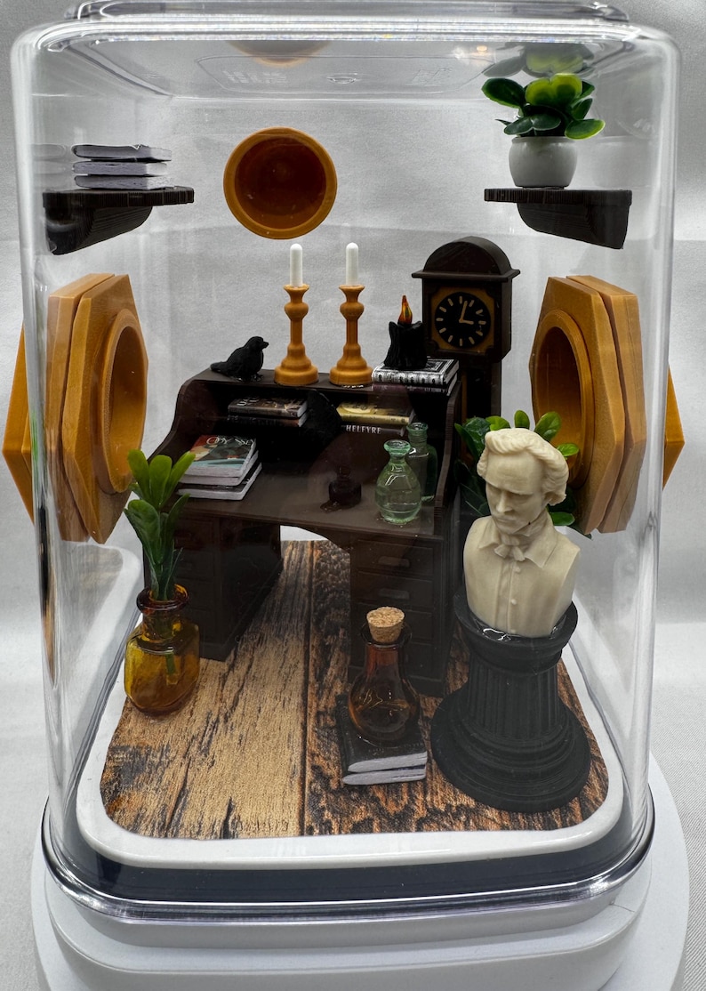 May include: Miniature diorama inside a clear dome. The scene includes a desk, bust, clock, candles, and books. The desk is dark brown, and the bust is white. The dome sits on a white base, and the background is a light gray.