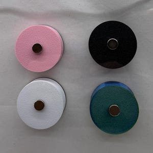 Puede incluir: Cuatro imanes redondos en rosa, negro, blanco y verde azulado. Cada im&aacute;n tiene un peque&ntilde;o centro met&aacute;lico circular. Los imanes est&aacute;n dispuestos en un patr&oacute;n cuadrado sobre un fondo blanco. Los imanes son probablemente para un refrigerador o una pizarra.