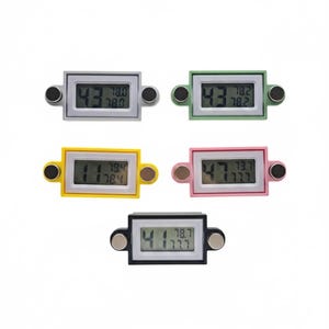 May include: Five small digital thermometers in various colors: gray, green, yellow, pink, and black. Each thermometer displays temperature readings and has two circular magnets attached. The thermometers are rectangular with rounded corners.