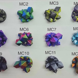 May include: A collection of twelve colorful, geometric crystal formations. Each cluster features a unique blend of colors, including blues, greens, purples, and golds. The crystals are arranged on a white surface, labeled MC1 through MC12.