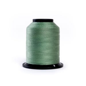 May include: A spool of sage green thread, tightly wound, sits on a black base. The thread has a subtle sheen, suggesting a smooth texture. The spool is cylindrical, with a flat top and bottom.