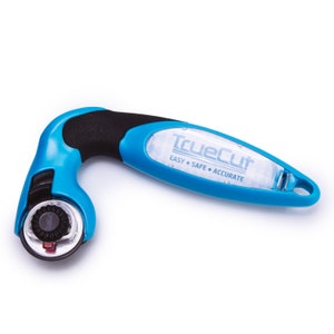 Puede incluir: Un cortador rotatorio azul y negro con un mango de pl&aacute;stico transparente que dice "TrueCut EASY &bull; SAFE &bull; ACCURATE".