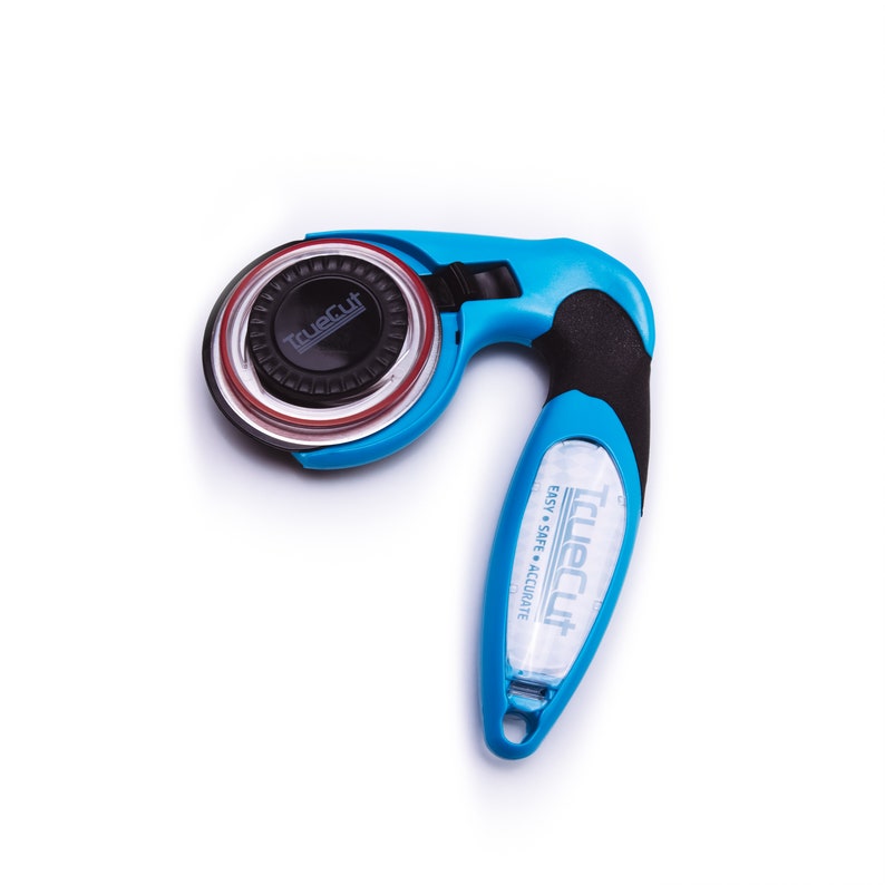 Puede incluir: Un cortador rotatorio azul y negro con un mango de pl&aacute;stico transparente. El mango tiene el texto "TrueCut Easy Safe Accurate" impreso en &eacute;l. El cortador est&aacute; dise&ntilde;ado para cortar tela.
