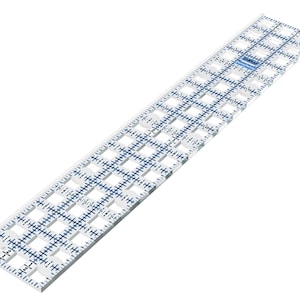 Könnte beinhalten: Ein transparenter Quilt-Lineal mit blauen Gittermarkierungen und Zentimeter-Maßen. Das Lineal hat ein Gittermuster mit ausgeschnittenen Quadraten zur Stoffausrichtung. Es ist für präzises Schneiden und Messen in Näh- und Quiltprojekten konzipiert.