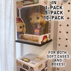 May include: Two Funko Pop! vinyl figures displayed on a pegboard wall. The top figure is Leslie Knope from Parks and Recreation, a 2021 Summer Convention Limited Edition. The bottom figure is a Star Wars character. The text "AVAILABLE IN 1-PACK 5-PACK 10-PACK FILIBUSTER LESLIE FOR BOTH SOFT CASES AND BOXES!" is visible in the image.
