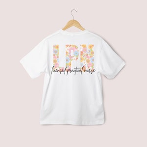 May include: White t-shirt with a floral design spelling out "LPN" and the text "licensed practical nurse" below.
