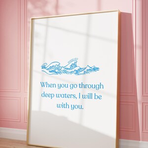 May include: A framed art print with a gold frame, featuring blue wave illustrations and the text "When you go through deep waters, I will be with you." The artwork is displayed against a pink wall.