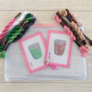 May include: A craft kit with two needlepoint canvases depicting drinks, framed in pink, alongside a selection of colourful embroidery threads and a mesh bag with a pink zip. A pink flower and small embellishment are also included.