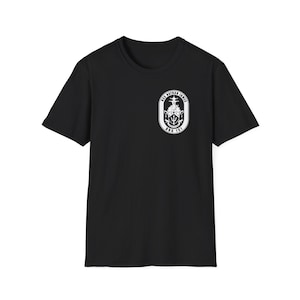 May include: A black short-sleeve t-shirt featuring a white circular emblem on the left chest. The emblem displays a ship silhouette, a trident, and the text USS NATHAN JAMES DDG 151 in a bold, clear font against a dark background.