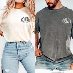May include: Two t-shirts, one white and one gray, with the words "MOM EST. 2024" and "DAD EST. 2024" printed on them.