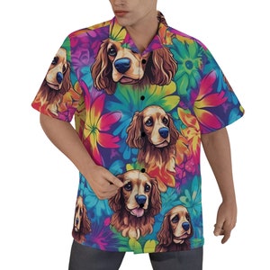 Puede incluir: Una camisa de manga corta con botones y un estampado floral colorido con una imagen repetida de un perro golden retriever. La camisa tiene un cierre de botones negros.