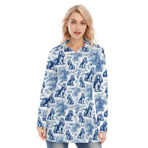 Puede incluir: Camisa de manga larga con un estampado de toile de Jouy azul y blanco que representa Cocker Spaniels. La camisa tiene cuello y un corte relajado, adecuada para ropa informal.