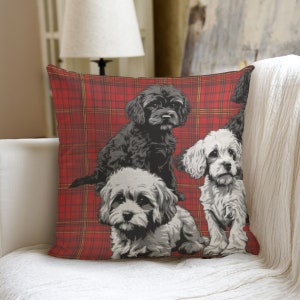 Op de afbeelding: Een rood en geel geruit kussen met een ontwerp van vier zwart-witte honden. De honden zitten en staan in een speelse pose.