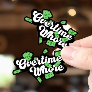 May include: Two black stickers with the text "Overtime Whore" in white script, surrounded by green dollar bills. The stickers are held up by a hand against a blurred background.