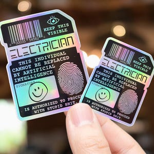 May include: Two holographic stickers with the text "ELECTRICIAN" and "THIS INDIVIDUAL CANNOT BE REPLACED BY ARTIFICIAL INTELLIGENCE." Each sticker has a fingerprint, a smiley face, and a barcode.