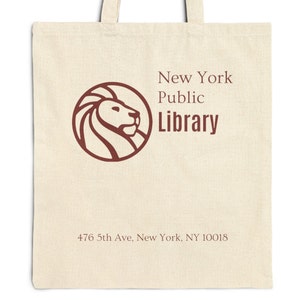 Puede incluir: Una bolsa de lona blanca con un logotipo de cabeza de león marrón y el texto "New York Public Library" y "476 5th Ave, New York, NY 10018".