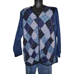 May include: A long-sleeved button-down cardigan featuring a patchwork design on the front with various shades of blue, including navy, light blue, and denim textures. The front panel displays a diamond pattern with visible white stitching.