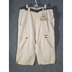 May include: Khaki-colored cargo shorts with multiple pockets and a dark blue waistband. The shorts have a tag attached with the number "02941" visible. The shorts are hanging on a hanger against a gray background.