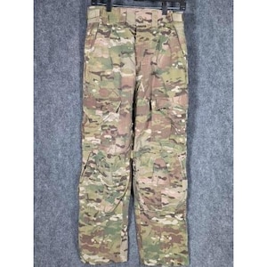 Peut inclure: Pantalon cargo camouflage avec plusieurs poches. Le pantalon est doté d'une fermeture boutonnée et de passants de ceinture. Le motif camouflage comprend des nuances de vert, de marron et de beige. Le pantalon est suspendu à un cintre noir sur fond gris.