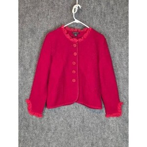 Könnte beinhalten: Eine leuchtend rote Jacke mit Rüschenkragen und -manschetten, die vorne mit Knöpfen geschlossen wird. Die Jacke hängt an einem weißen Kleiderbügel vor grauem Hintergrund. Die Knöpfe haben die gleiche Farbe wie die Jacke.