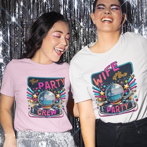May include: Two women wearing matching pink and white t-shirts with a disco ball graphic and the text "The Party Crew" and "Wife of the Party".