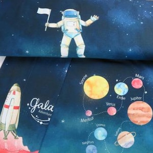 Könnte beinhalten: Stoff mit Weltraumthema mit einem Astronauten, der eine Flagge vor einem Sternenhintergrund hält. Das Design umfasst eine Rakete, Planeten und den Text "Gala Adventure".