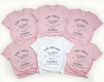 May include: Six pink t-shirts with black text and a graphic of a cocktail glass. The text on the shirts reads "Die Crew" and "Die Braut" with the year "2025" and the name "Leonies" on each shirt.