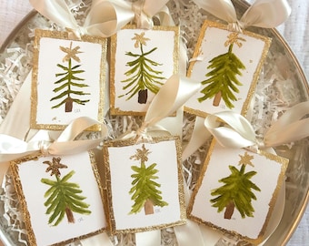 May include: Six handmade Christmas tree decorations with gold trim and green watercolour paint. Each decoration has a gold star on top and the letters "C&R" at the bottom.