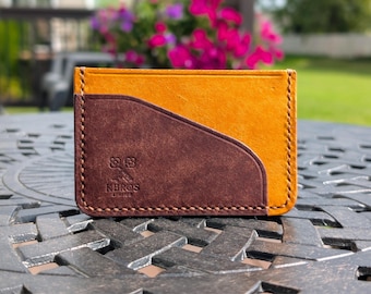May include: A handcrafted leather cardholder in a bi-color design. The top section is a golden-yellow, while the lower section and card slot are a deep brown. The cardholder features stitched edges and the "NEROS LEATHER" logo.