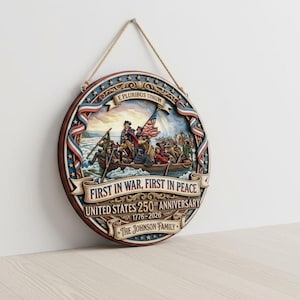 May include: A round wooden wall hanging with a patriotic theme. The design features a historical scene with a flag and the text "First in War, First in Peace, United States 250th Anniversary 1776-2026". It is suspended by a natural fiber cord.