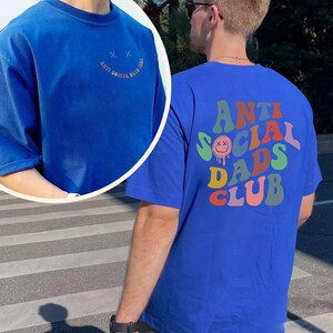 May include: Royal blue t-shirt with the text "ANTI SOCIAL DADS CLUB" in a retro font on the back. The front of the shirt has a small smiley face and the words "ANTI SOCIAL DADS CLUB" in a semi-circle.