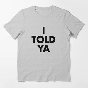 Könnte beinhalten: Ein graues T-Shirt mit dem Text "I TOLD YA" in Schwarz gedruckt.