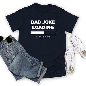 May include: A navy blue t-shirt with white text that reads "Dad Joke Loading" with a progress bar and the words "Please Wait" underneath.