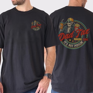May include: Black t-shirt with a graphic on the front and back. The front graphic is a circular design with the text "Dad Tax". The back graphic features a skeleton wearing sunglasses and a hat, holding a drink and fries, with the text "Dad Tax Making Sure It's Not Poison".