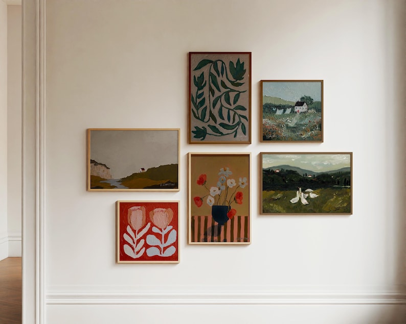 May include: A gallery wall with six framed paintings. The paintings feature a variety of subjects, including flowers, landscapes, and abstract designs. The paintings are arranged in a symmetrical pattern on a white wall.