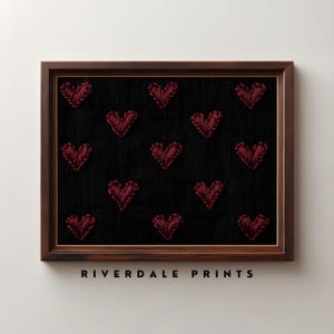 Puede incluir: Impresión enmarcada con fondo negro y un patrón de corazones rojos bordados. El marco es de color marrón oscuro, con el texto "RIVERDALE PRINTS" en la parte inferior.