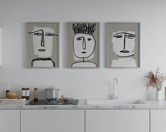 May include: Three framed abstract art prints. Each features a minimalist face design with black lines on a light gray background. The artwork is displayed above a kitchen countertop.