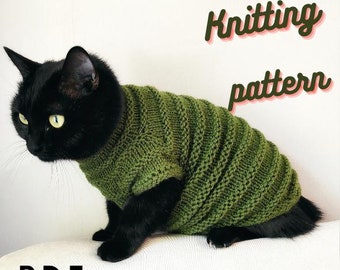 May include: A black cat wearing a green knitted sweater. The sweater has a cable knit pattern. The image includes the text "Knitting pattern PDF".