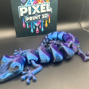 Peut inclure: Un gecko imprimé en 3D bleu et violet avec une finition texturée. Le gecko est posé avec ses pattes tendues et sa queue enroulée.