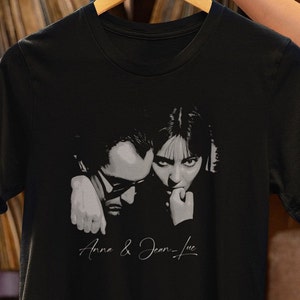 Könnte beinhalten: Schwarzes T-Shirt mit einem Schwarzweißbild von zwei Personen. Der Text "Anna & Jean-Luc" ist in Weiß unter dem Bild aufgedruckt.