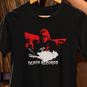 May include: Black t-shirt with a red and white graphic of a person holding a bird with the text "DEATH RECORDS" underneath.